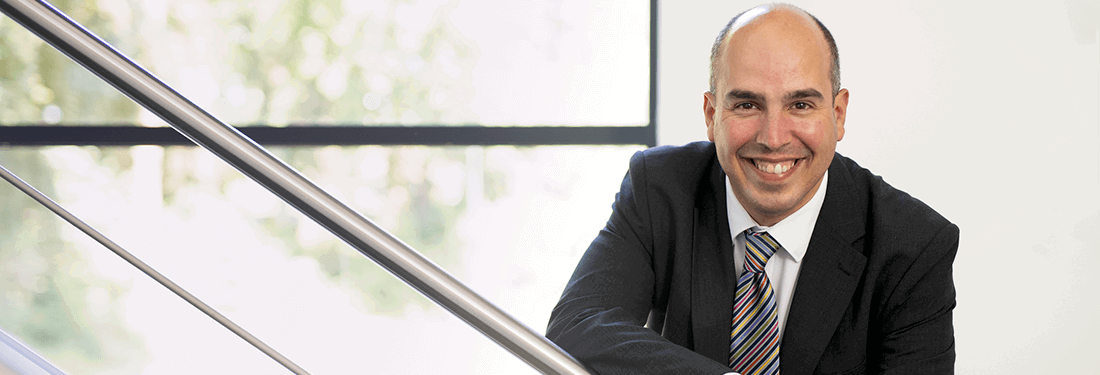 Professor Adam Boddison standing on stairs, smiling