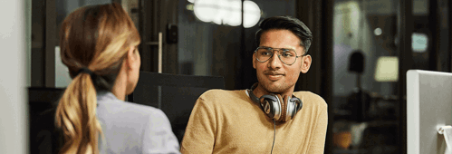 Two colleagues in a discussion, one with headphones around their neck