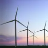 Wind turbines silhouetted against a vibrant sunset