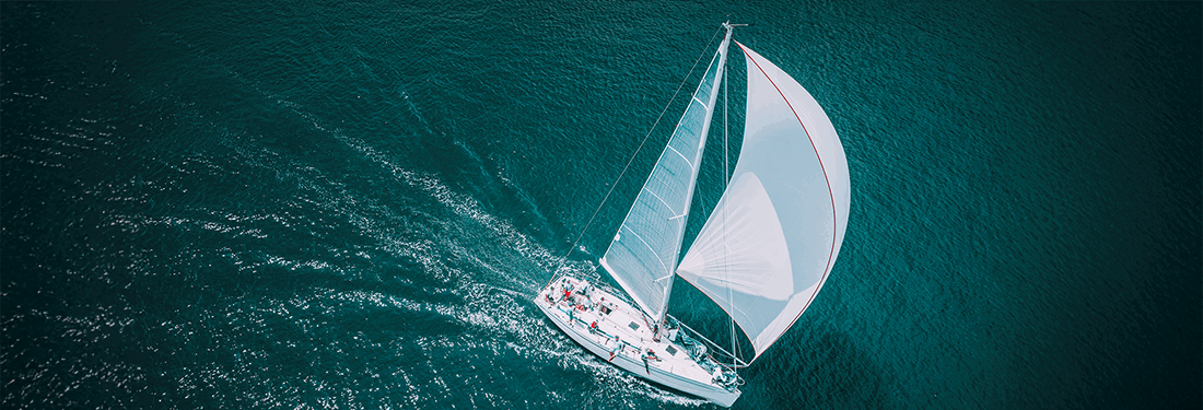 Regatta sailing ship yachts with white sails at opened sea. Aerial view of sailboat in windy condition.
