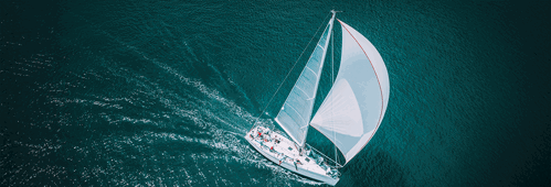 Regatta sailing ship yachts with white sails at opened sea. Aerial view of sailboat in windy condition.